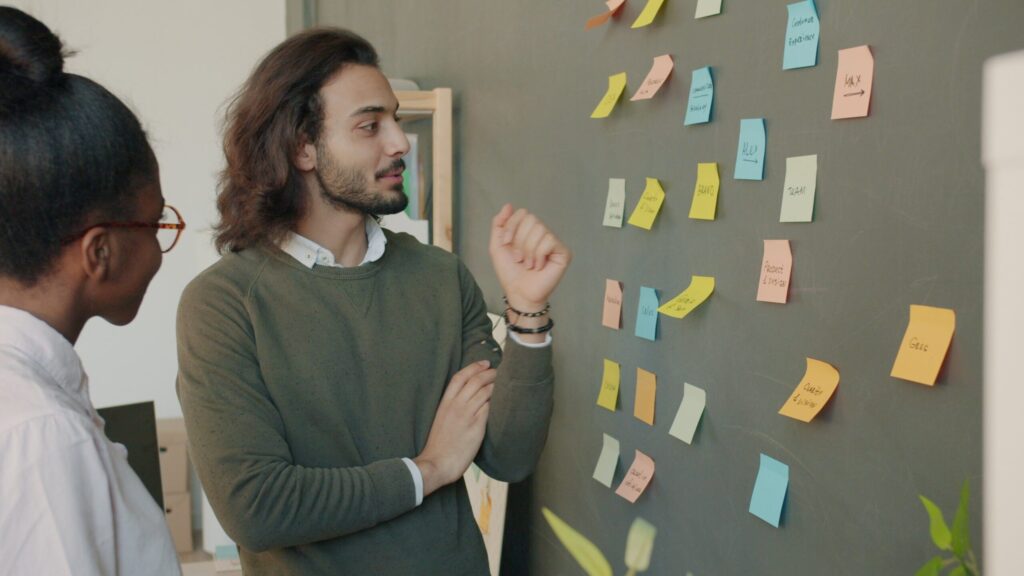 Team brainstorming session with sticky notes on a whiteboard, listing reasons a project could fail during an inversion thinking exercise